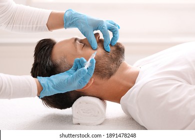 Side view of bearded man getting beauty injection at aesthetic clinic. Plastic surgeon injecting anti-aging filler in handsome man cheeks. Male cosmetology, aesthetic medicine concept