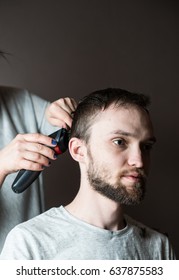 Side view of bearded man getting haircut by hairdresser at the barbershop