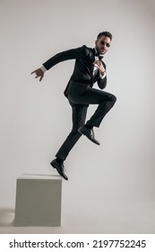 Side View Of Bearded Man In Tuxedo Jumping To New Beginnings And New Opportunities On Grey Background