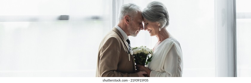 Side View Of Bearded Middle Aged Groom Holding Wedding Bouquet With Happy Bride In White Dress, Banner