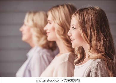 Side view of beautiful women generation: granny, mom and daughter smiling while standing in a row
