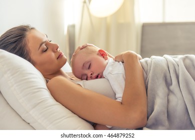 Side View Of Beautiful Young Mom And Her Cute Little Baby Sleeping In Bed At Home