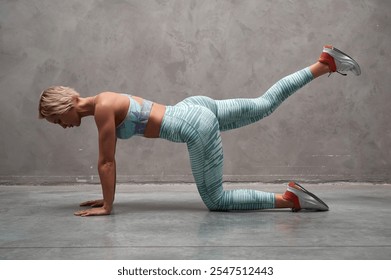 Side view of beautiful young sports lady doing table pose and exercises with leg in fitness hall. Female doing gymnastic stretches in gym. - Powered by Shutterstock