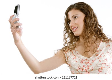 Side View Of A Beautiful Young Woman Holding A Cell Phone In The Air While Standing Against A White Background, Isolated.