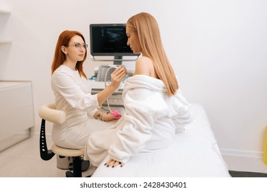 Side view of beautiful young woman getting breast examination during appointment at hospital. Female doctor using ultrasound scanner on patient breast. Concept of cancer awareness mammalogy sonography - Powered by Shutterstock