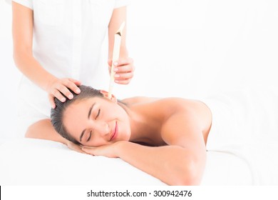 Side view of a beautiful young woman receiving ear candle treatment at spa center - Powered by Shutterstock