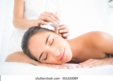 Side view of a beautiful young woman receiving ear candle treatment at spa center - Powered by Shutterstock