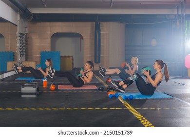 Side View Of Beautiful Young Women Exercising Russian Twist With Medicine Ball From Sitting Position For Strong Abs