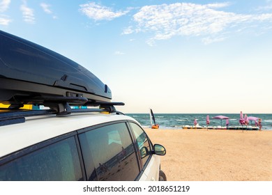 Side View Of Big Family White Suv Van Car With Big Rooftop Cargo Rack Box At Scenic Sand Seaside Campsite Camp Coast Of Sea Or Ocean Sky On Background. Accessory Rental Travel Trip Vacation Concept