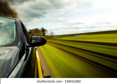 Side View Of Black Car Driving On The Country Road.