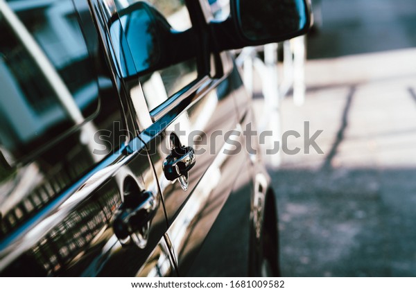 Side view of black\
executive luxury mini van car parked on the empty street focus in\
the door hande