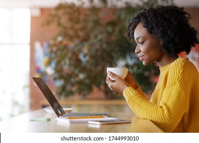 Side View Of Black Lady Enjoying Morning Coffee And Checking Emails On Laptop, Cafe Interior, Empty Space