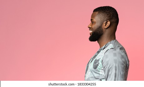 Side View Of Black Smiling Guy In African Shirt Looking At Free Space On Pink, Studio Shot, Panorama. Excited African American Young Man Staring At Great Deal Over Colorful Background