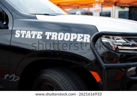 Side view black SUV State Trooper patrol vehicle with push bumper steel frames mounted used to push disabled vehicles away from danger or clear the roadway ensuring public safety, police bullbars. USA