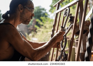 Side view of a blacksmith checking the measurements of a grating in his workshop. Blacksmith concept. - Powered by Shutterstock