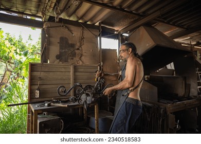 Side view of blacksmith shaping a decorative grille in his workshop. Blacksmith concept. - Powered by Shutterstock