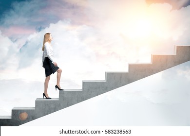 Side View Of A Blond Woman In A Black Skirt And A White Blouse And Climbing Stairs To The Sky. Concept Of A Road To Success In Business.