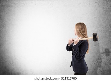 Side View Of Blond Woman With Sledgehammer About To Smash Concrete Wall. Concept Of No Limits. Mock Up