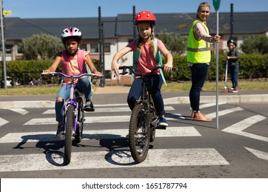 Side view of a blonde Caucasian woman wearing a high visibility vest and holding a stop sign, standing in the road on a pedestrian crossing and stopping the traffic while a Caucasian and an African - Powered by Shutterstock