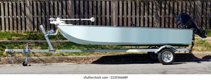 Side View Of Blue Fishing Boat On Trailer Parked On Residential Neighborhood Street.