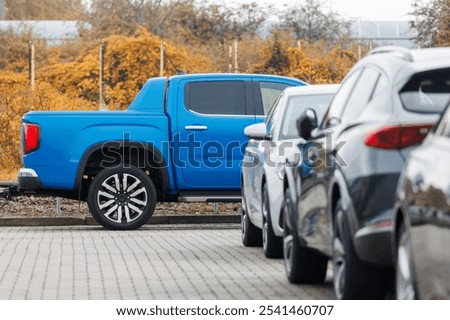 Side view of blue new ev pickup truck parked at outdoor parking lot automobile dealer or parking place against autumn foliage. Modern SUV electric vehicle outside