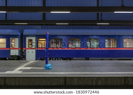 Side view of blue passenger train at empty platform railway station in Europe