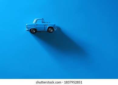 Side view of a Blue toy car on a blue background with long and side shadow.