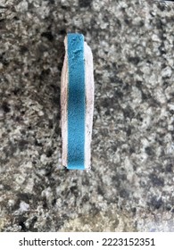 Side View Of A Blue And White Cleaning Sponge On A Granite Countertop