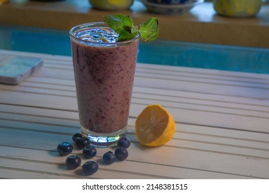 Side view of blueberry smoothies on white antural wood table.