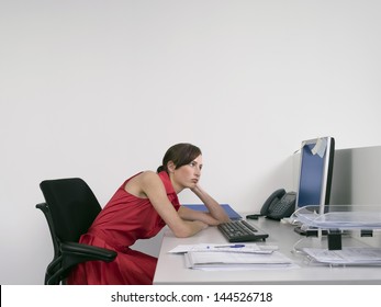 Side view of a bored female office worker looking at notes on computer monitor at desk