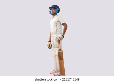 Side view of a boy in cricket uniform standing with bat looking elsewhere