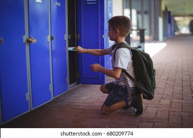 Side view of boy keeping books in locker at school corridor - Powered by Shutterstock