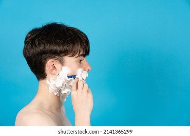 Side View Of Boy Shaving Face  Isolated On Blue Background