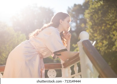 Side view of bride using mobile phone while leaning on railing in balcony