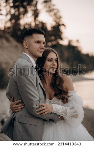 Side view of bride wearing white dress, groom wearing costume having wedding ceremony. Happy couple getting marries, smiling, looking forward. Concept of wedding and happiness.