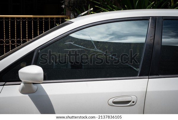 Side view of broken\
car windshield. Damaged glass with traces of something impact on\
car windshield.
