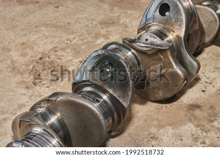Side View Broken Crankshaft with Engine Oil Stain of Truck Engine on Concrete Floor