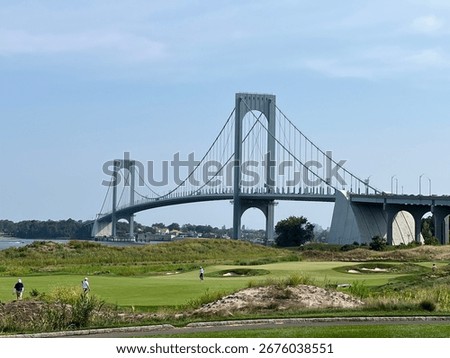 A side view of the Bronx Whitestone Bridge in New York City connecting the Bronx with Whitestone, queens. A golf course is in the foreground.