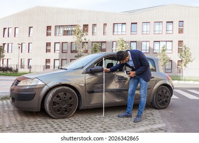 Side View Of Brunette Male Auto Insurance Adjuster Inspecting A Vehicle That Has Been In An Accident Wreck, Wearing Jeans And Jacket, Assesses The Damage To The Car. Outdoor Shot.