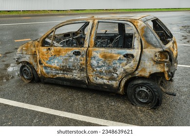 Side view of a burnt and abandoned rusty van and a broken headlight. Burned out car in street. The skeleton of a burnt car. Shallow depth of field