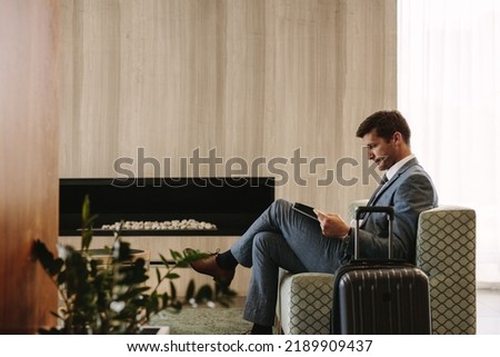Side view of business executive reading a magazine while waiting for his flight at airport lounge. Man at airport waiting area reading a magazine.