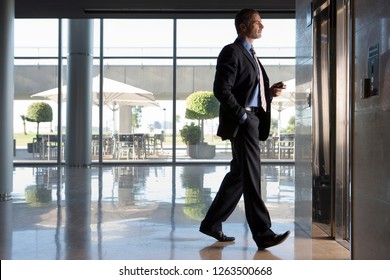 Side View Of Businessman Entering Lobby Elevator In Modern Office Building