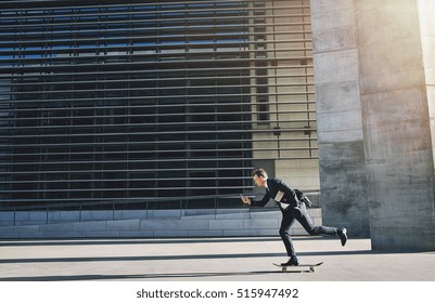 Side view of a businessman rolling on a skateboard and using a phone - Powered by Shutterstock