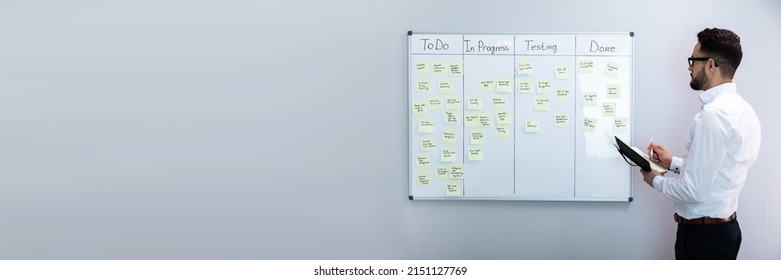 Side View Of Businessman Writing On Sticky Notes Attached To White Board In Office - Powered by Shutterstock