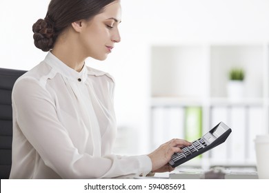 Side View Of A Businesswoman With Brown Hair Sitting At Her Workplace And Working With A Calculator. Concept Of Accountant Work.