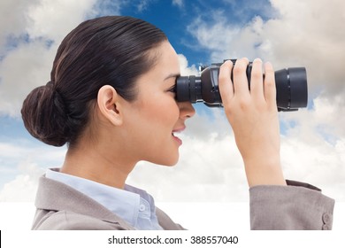 Side view of a businesswoman looking through binoculars against blue sky