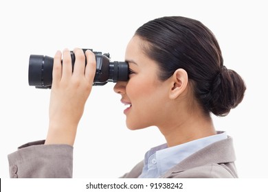 Side view of a businesswoman looking through binoculars against a white background