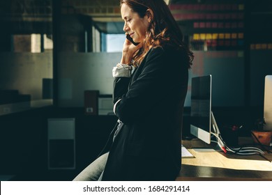 Side View Of A Businesswoman Talking On Mobile Phone In Office. Woman Entrepreneur On A Phone Call In Office.