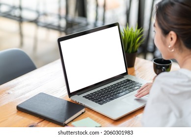 Side view of a businesswoman working on a laptop blank white screen at office. Mock up.