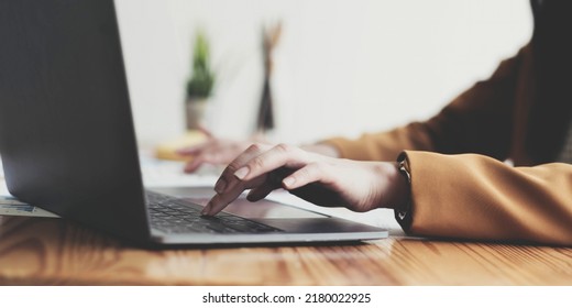 Side View Of Businesswoman's Hands Using Laptop Computer Placed On Messy Office Desktop
